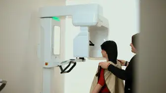 Patient having a panoramic X-ray taken with an assistant nearby