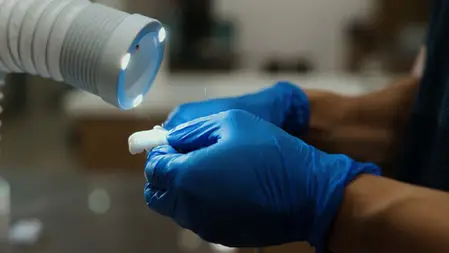 Gloved hand holding a dental mirror under the treatment light