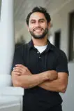 Team member in a black polo standing with arms crossed